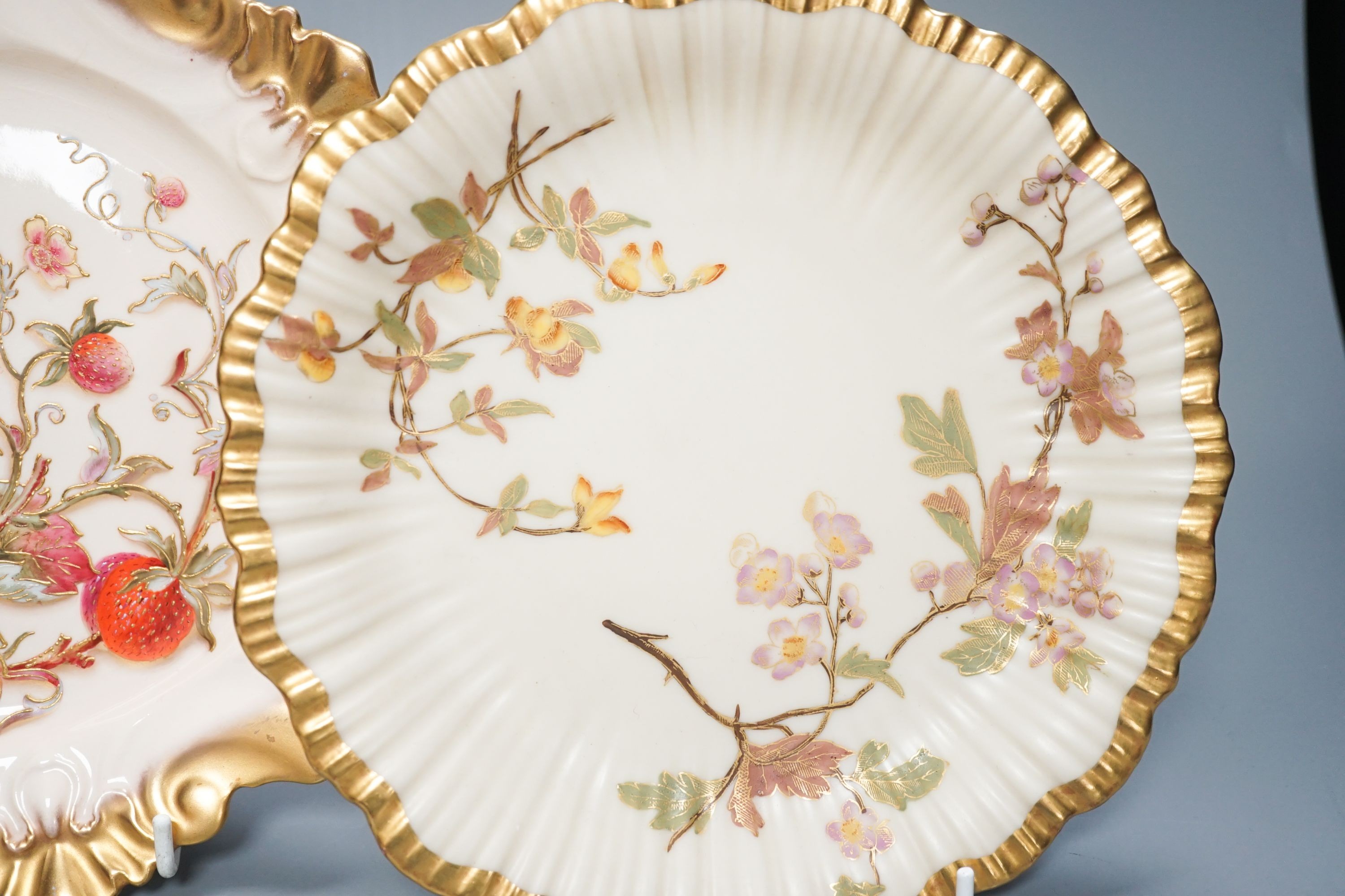 A Royal Worcester fine moulded plate painted and gilded with Strawberries by William Hale, signed WH verso, date mark 1890 and a pair of ivory moulded plates painted and gilded with tree branches, largest diameter 23cm